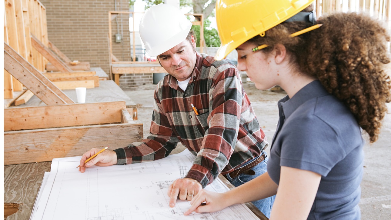 Man and woman looking at blue prints at a construction site
